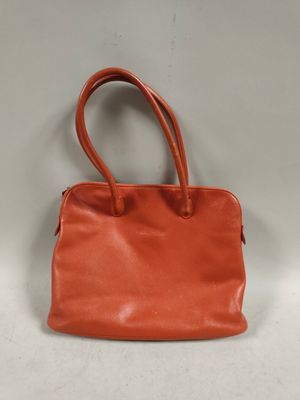 an orange leather handbag on a white background