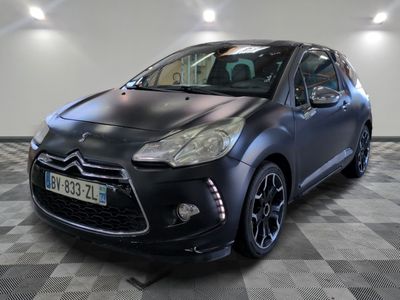 La voiture noire est garée sur le sol à damier du garage.