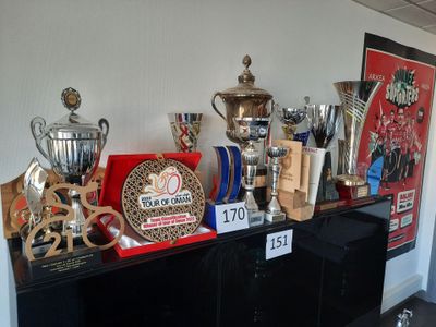 de nombreux trophées exposés sur une étagère noire dans une pièce
