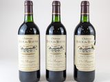 trois bouteilles de vin rouge posées l'une à côté de l'autre sur une surface blanche