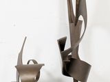 three metal sculptures that are sitting on a white surface