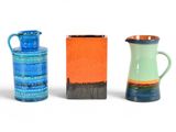 trois vases de couleurs différentes posés les uns à côté des autres sur une surface blanche