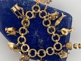 an image of a gold bracelet with charms on a blue stone