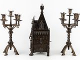 three metal candelabs with a clock on each of them