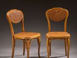 two wooden chairs with wicker seats on a grey background