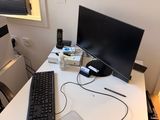 a desk with a keyboard, mouse, headphones and a monitor on it
