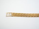 a close up of a gold bracelet on a white surface