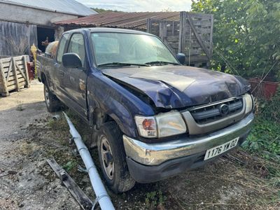 a truck that has been damaged and is parked in front of a barn