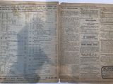 an old newspaper is open on a table with a shadow of a person