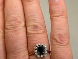 a woman ' s hand holding a ring with a black and white diamond