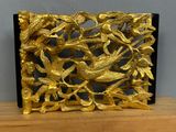 a gold plate with birds and leaves on it