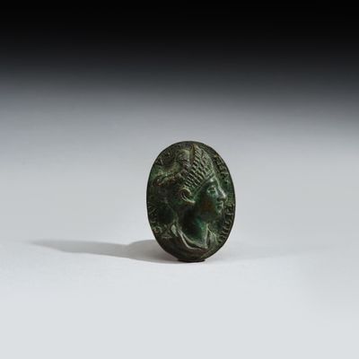 une ancienne pièce de monnaie en bronze sur laquelle figure la tête d'un homme