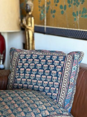 a brown leather couch with a blue and pink pillow