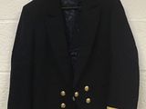 a black jacket with gold stripes and buttons hanging on a white wall