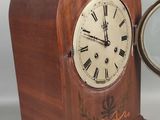 une horloge en bois avec des chiffres romains et un miroir posé sur la table