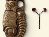 a metal object that looks like a seahorse and a bead