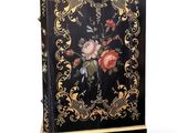 a black and gold painted cabinet with flowers on it