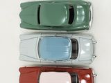 four toy cars are lined up in a row on a white surface