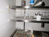 a metal shelf with empty glasses on it in a kitchen