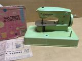 a green sewing machine sitting on a table next to a box