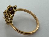 a close up of a gold ring with a red stone in it