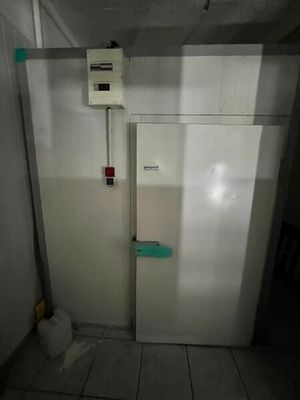a white refrigerator in the corner of a room with a light on