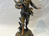 statue en bronze représentant un garçon avec un oiseau, posée sur un socle en bois