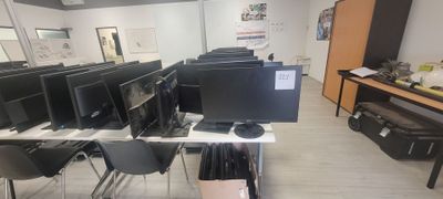 des rangées d'écrans d'ordinateur posés sur les bureaux d'une salle de classe