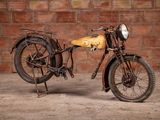 a old motorcycle that is parked in front of a brick wall