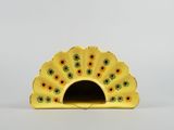 a small yellow fan with sunflowers on it on a white surface