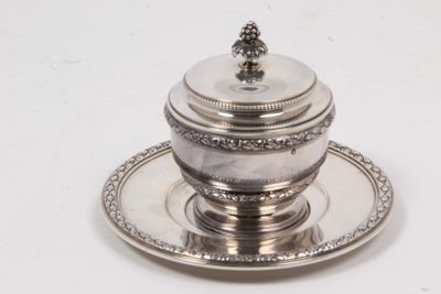 a silver plate with a silver lid on a saucer