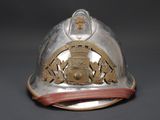 a silver fireman ' s helmet with a gold emblem on it