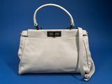 a white leather handbag on a blue background