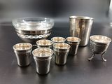 several shot glasses and a silver cup on a table