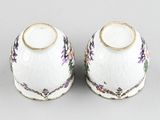pair of porcelain vases with floral designs on them on a gray surface