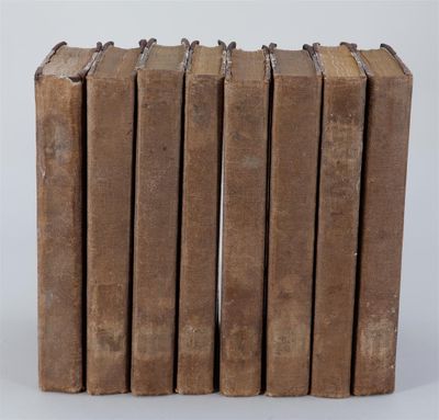 six vieux livres empilés sur une surface blanche