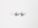 une paire de boucles d'oreilles à clous ornées de diamants blancs posées sur une surface blanche