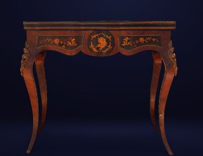 une table ancienne en bois dont le plateau est orné de motifs noirs et dorés