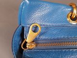 a blue purse that has a gold zipper on it