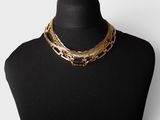 a black mannequin with a gold chain and red beads