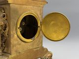 a gold clock that is sitting on a stand
