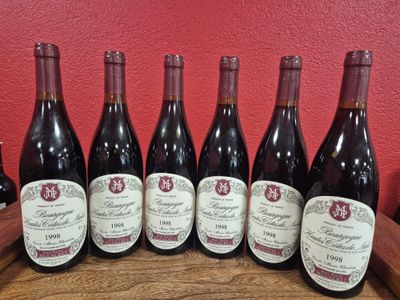 six bouteilles de vin sont alignées sur une table en bois