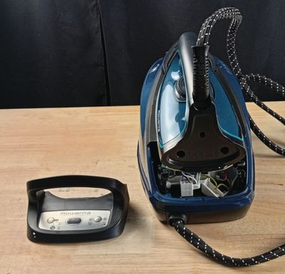 un fer à repasser à vapeur bleu et noir posé sur une table en bois