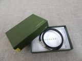 a green box with a black and white bracelet inside of it