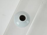 a white vase sitting on a white table with a black lid