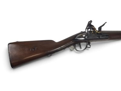 un vieux fusil exposé sur une surface blanche