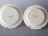 two white plates with black writing on them sitting on a table