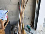 a pile of brooms and other tools on the sidewalk