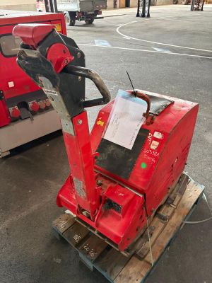 une machine rouge posée sur une palette dans un parking
