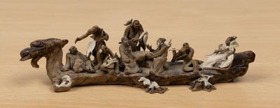 figurines of a group of people sitting on a piece of wood